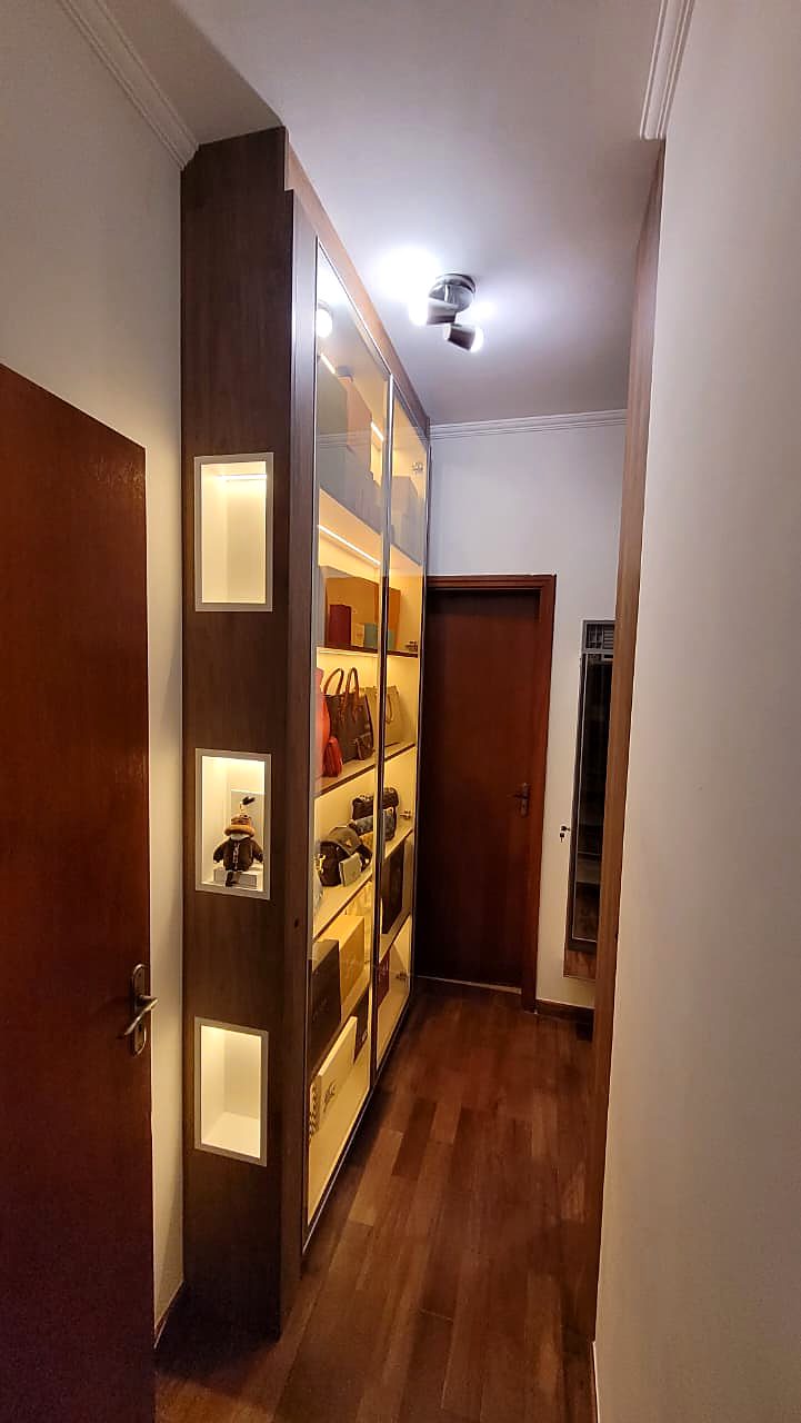 Corredor com closet vitrine e nichos iluminados em residência na Aldeia da Serra