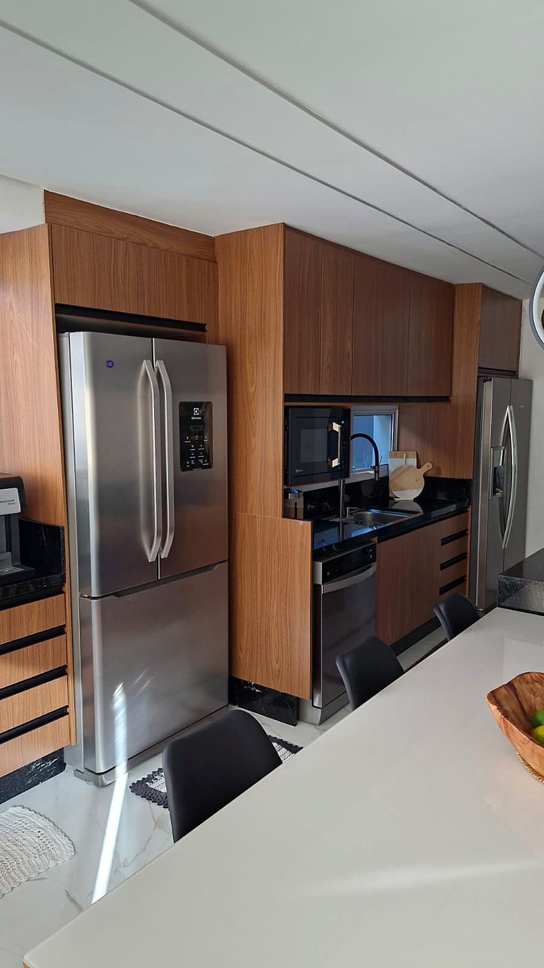 Cozinha planejada em madeira e preto com torre de eletros