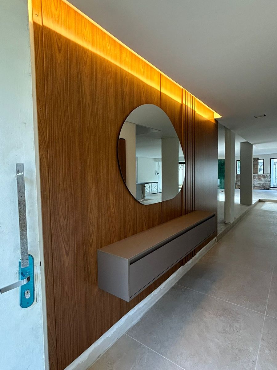 Hall de entrada com painel ripado e espelho orgânico